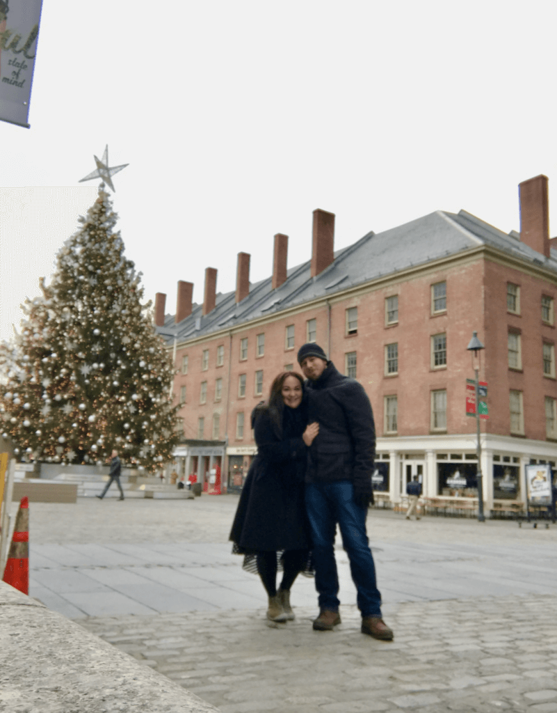 Elle and husband standing by the South St Seaport Christmas tree in NYC