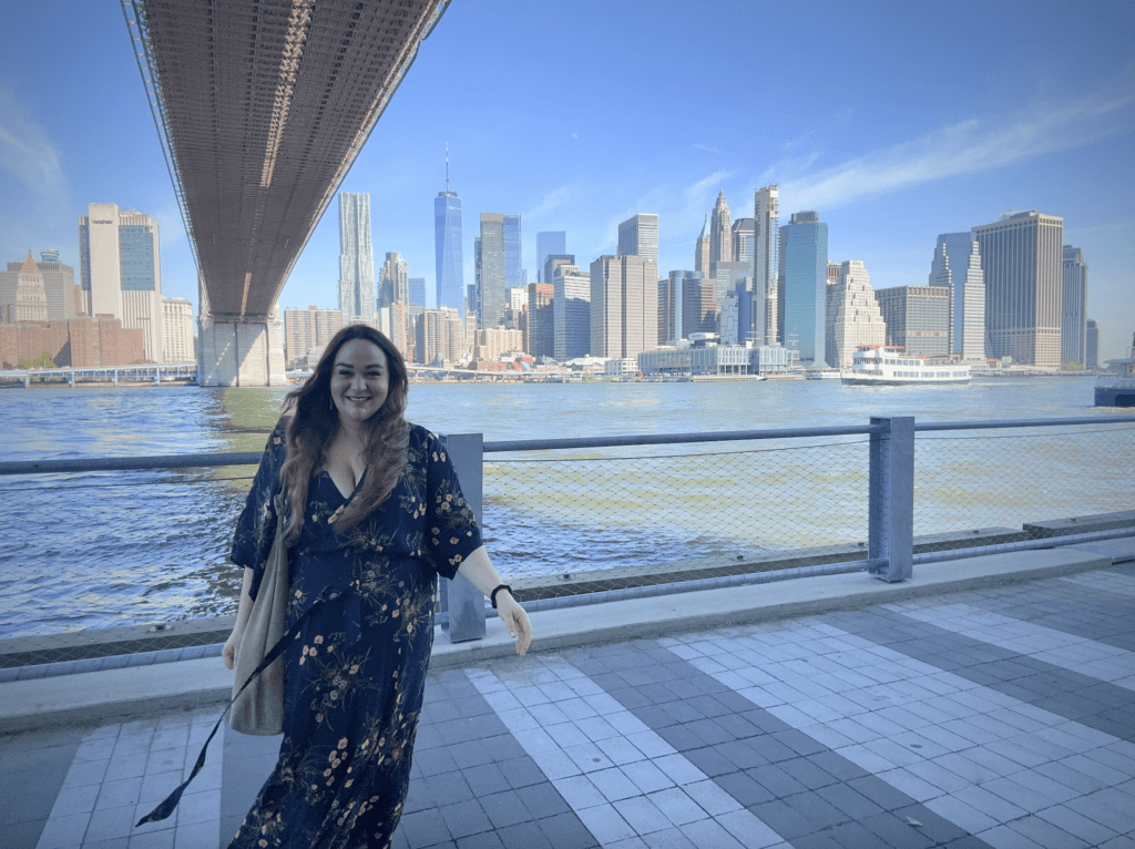 Elle posing for a photo in front of the NYC skyline, as seen from DUMBO.