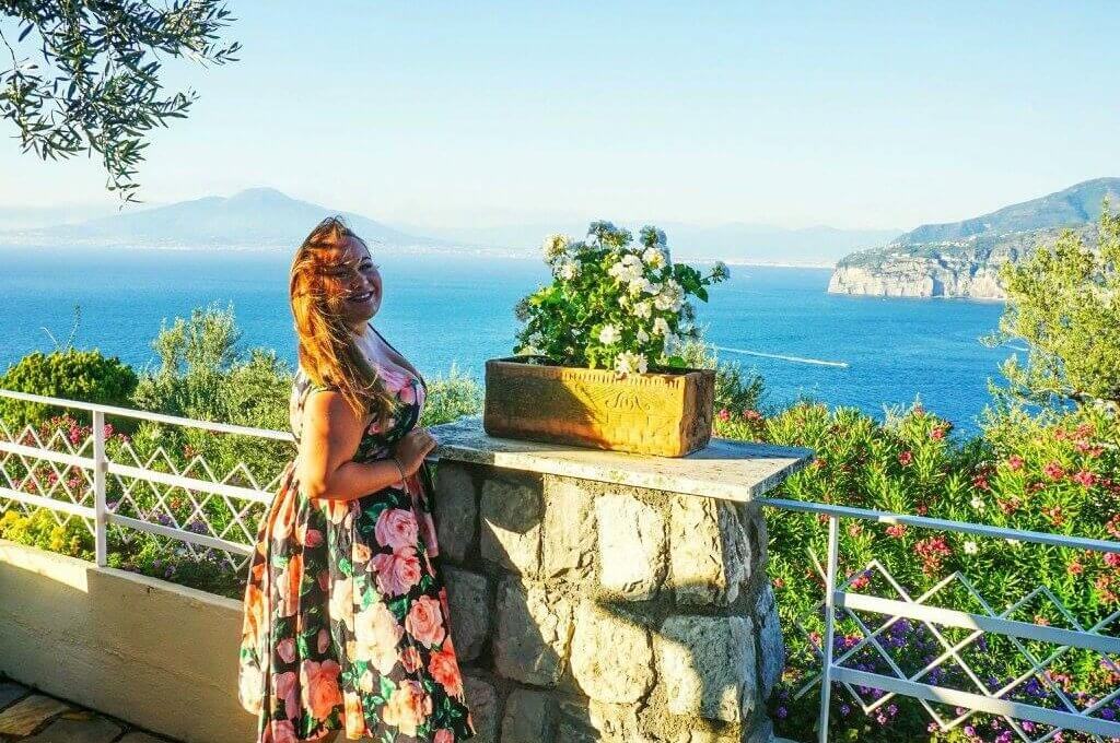 a woman stood in a summer dress in front of the italian sunset