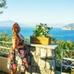 a woman stood in a summer dress in front of the italian sunset