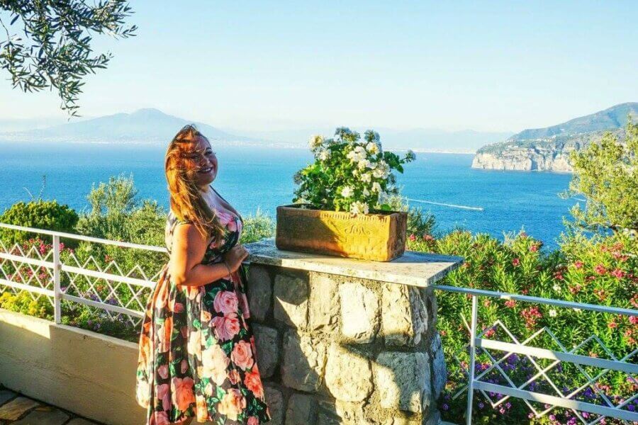 a woman stood in a summer dress in front of the italian sunset