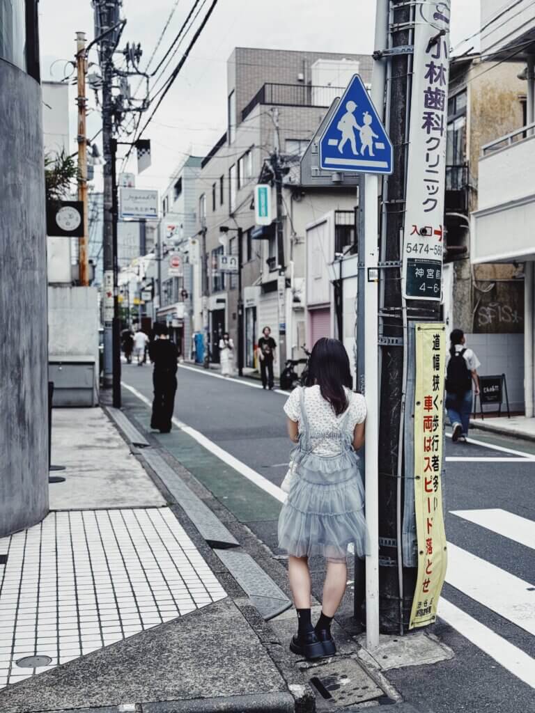 A girl standing in a grey street in Tokyo.